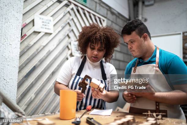 medewerkers die bij ambachtelijke pakhuis het controleren van speelgoed werken - syndroom van down stockfoto's en -beelden