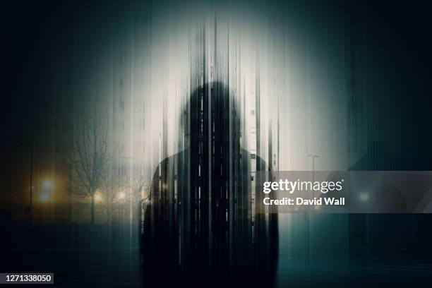 a double exposure of a silhouette of a mysterious hooded figure without a face, in a city at night. with a glitch, edit - crime stock pictures, royalty-free photos & images