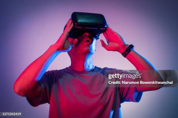 the man playing vr goggle with colorful lighting - young businessman using a virtual screen stockfoto's en -beelden