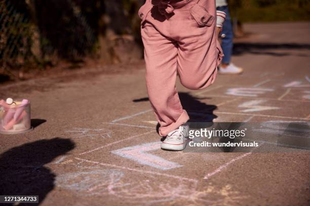 low section of little girl jumping hopscotch outdoors in street - hopscotch stock pictures, royalty-free photos & images