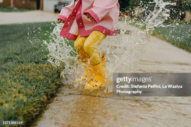 little girl jumping in a big puddle - poça imagens e fotografias de stock