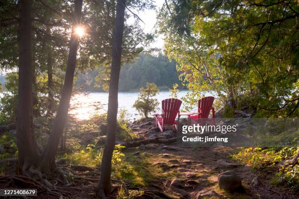 rode muskokastoelen bij bruce peninsula national park, tobermory, canada - adirondack chair stockfoto's en -beelden