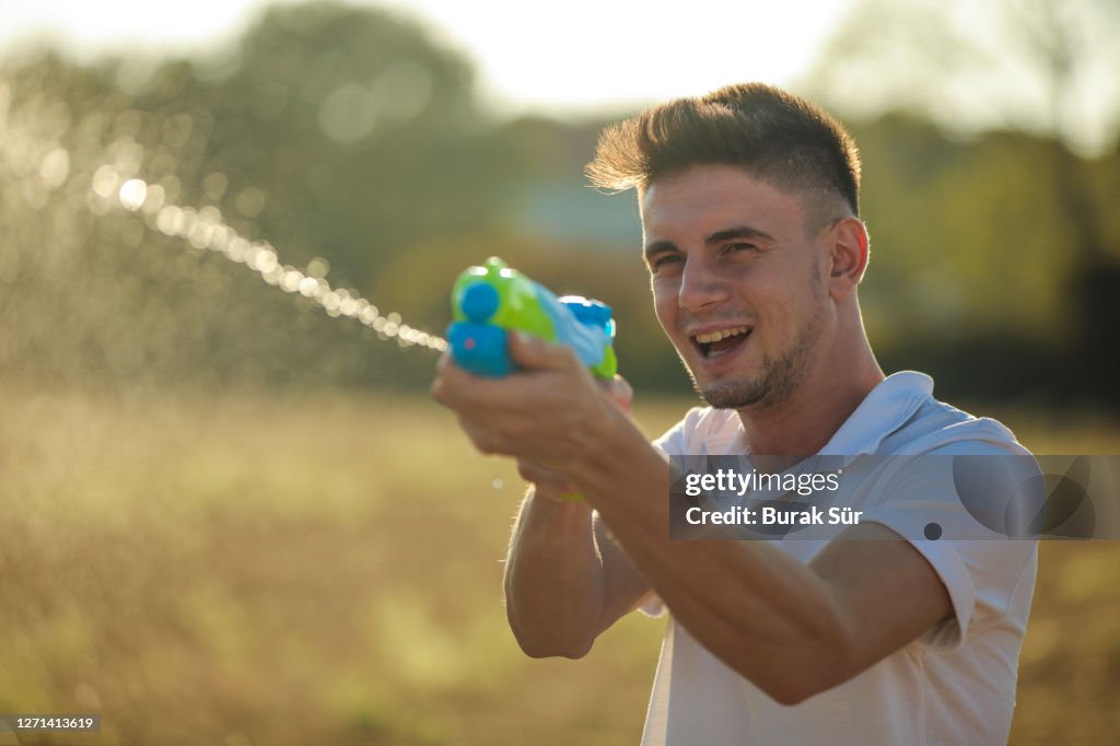 Junger Mann mit Wasserpistole Spaß