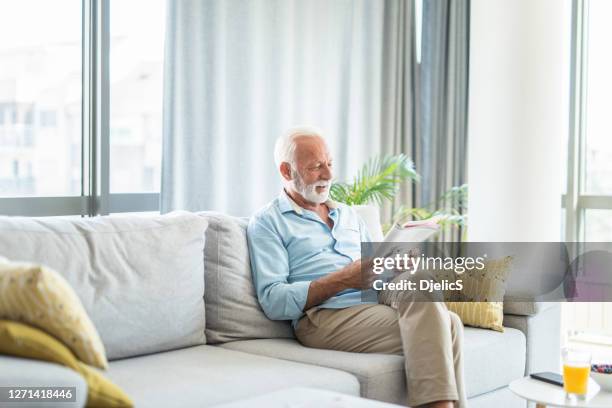 senior man reading a magazine at home. - one senior man only stock pictures, royalty-free photos & images