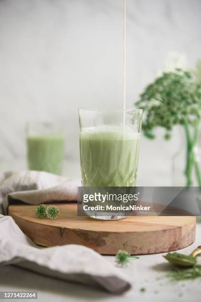 iced green matcha tea and pouring milk in latte glass on white table. space for text. close u - matcha tea stock pictures, royalty-free photos & images