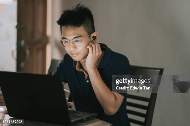 asian chinese teenage boy listening to music with bluetooth earphone and laoptop at home - e learning asian stock pictures, royalty-free photos & images