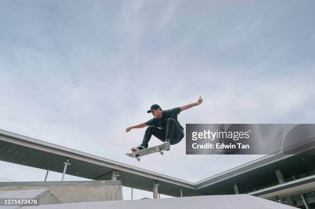skateboarder asiático en acción en el aire - patinar fotografías e imágenes de stock