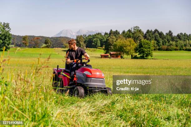 young mandriving a tractor on a lawn - lawnmower engine stock pictures, royalty-free photos & images