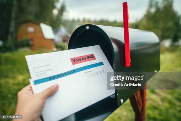 close-up of woman's hand putting or receiving letter with voting ballot near a mailbox near her house - voting by mail stock pictures, royalty-free photos & images