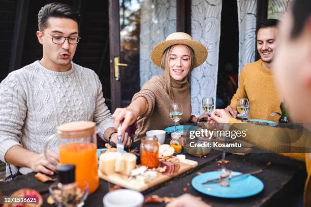 hungry young modern woman picking a cheese from cheese board during brunch with her friends - cheese plate stock pictures, royalty-free photos & images