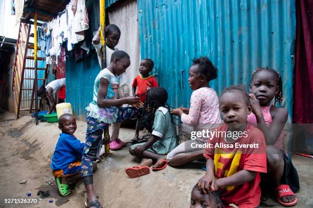 Children braid hair and play in the streets on July 9, 2020 in Nairobi, Kenya. Since school has been out, kids fill the streets of Mathare informal...