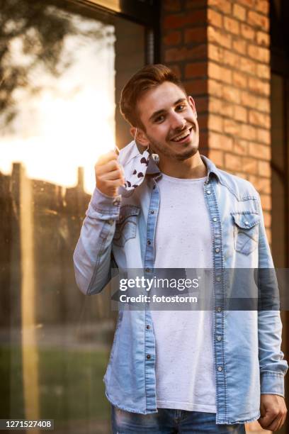 smiling while removing his protective face mask - removing surgical mask stock pictures, royalty-free photos & images