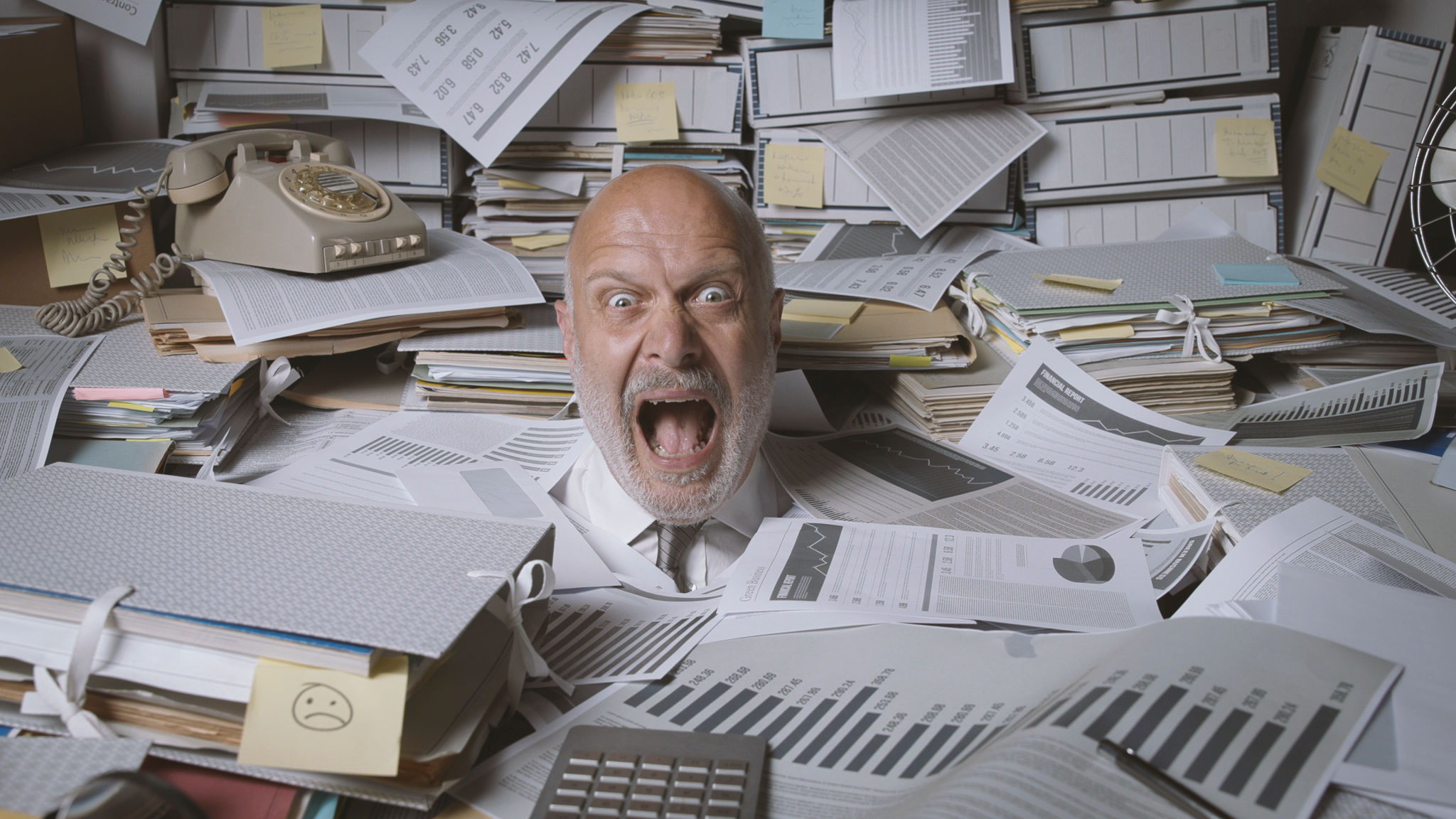 Stressed businessman buried under a lot of paperwork Stressed businessman buried under a lot of paperwork
