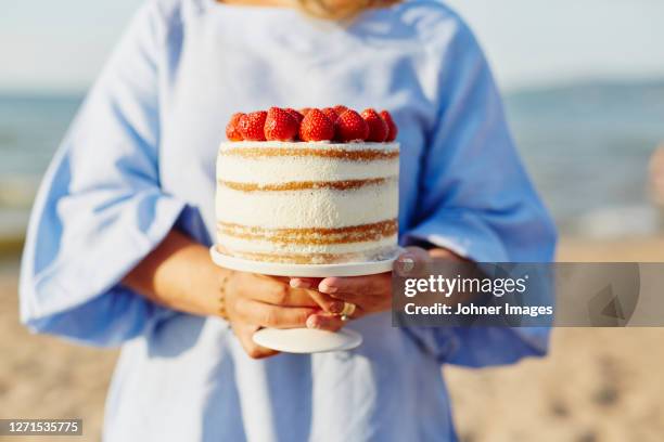 woman holding cake with strawberries - kuchenboden stock-fotos und bilder