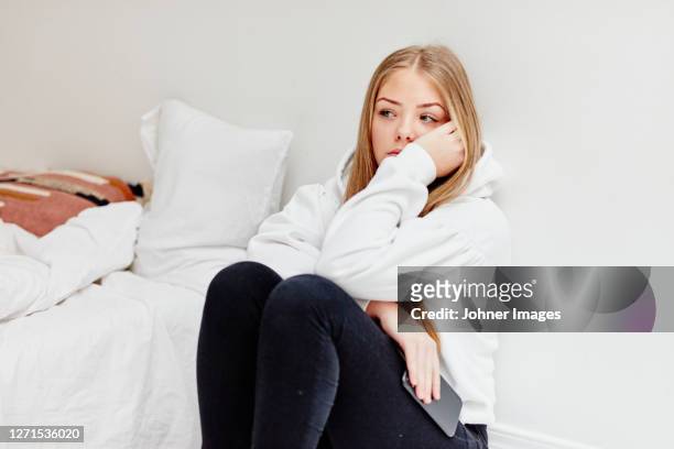 worried woman sitting in bedroom - smart stockfoto's en -beelden