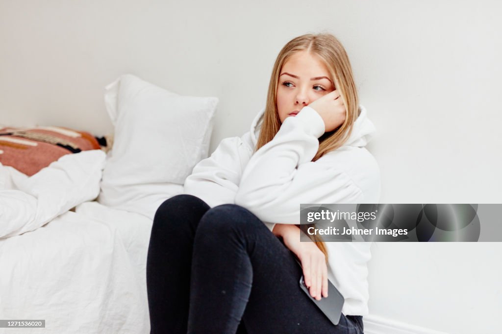 Worried woman sitting in bedroom