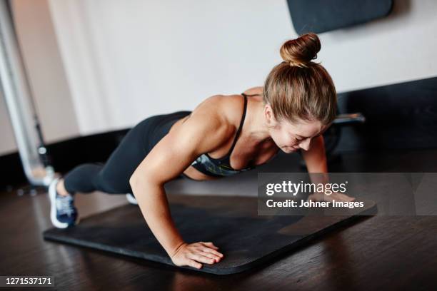 woman doing push-ups in gym - flexiones fotografías e imágenes de stock