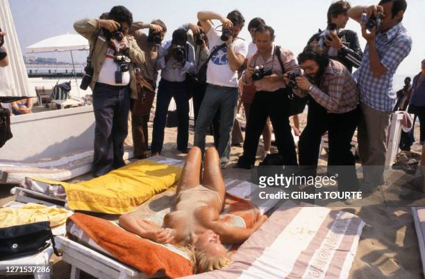 Photographes photographiant une femme posant nue dur la plage, pendant le festival du cinéma de Cannes, dans les Alpes-Maritimes, en 1979, France.