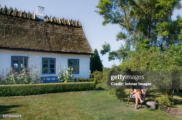 woman relaxing in garden - thatched roof stock-fotos und bilder