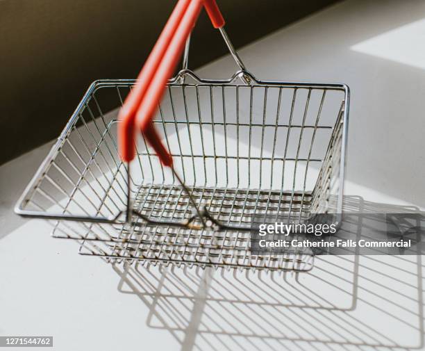 empty metal shopping basket casting shadow - convenience store counter stockfoto's en -beelden