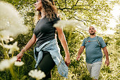 Caucasian couple walking in the park. Young woman and overweight man walking through the woods.