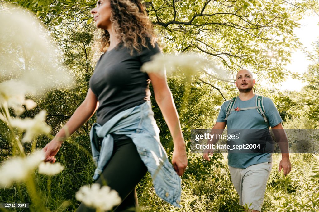 Caucasian couple walking in the park. Young woman and overweight man walking through the woods.