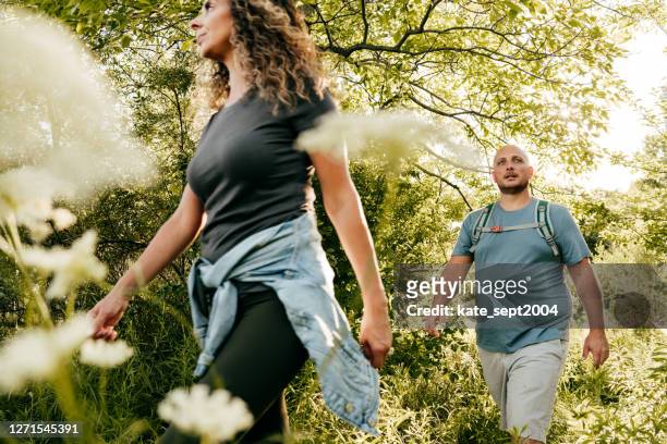 kaukasiska par promenader i parken. ung kvinna och överviktig man som går genom skogen. - walking bildbanksfoton och bilder