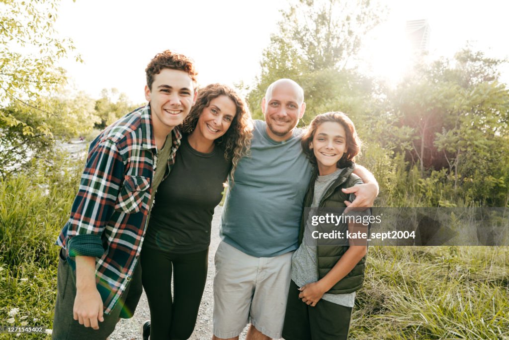 Family bonding and having a fun time together. Siblings and parents embracing and smiling at the camera.