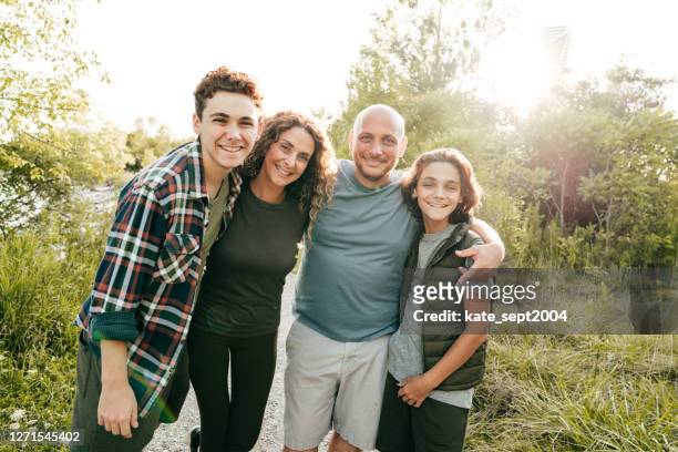 family bonding and having a fun time together. siblings and parents embracing and smiling at the camera. - four people stock pictures, royalty-free photos & images