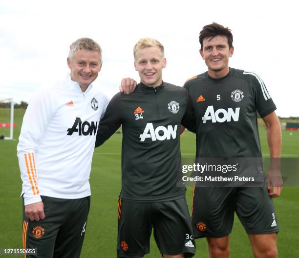 Donny van de Beek of Manchester United poses with Manager Ole Gunnar Solskjaer and Harry Maguire after a first team training session at Aon Training...