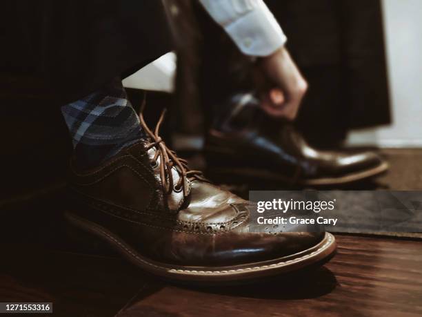 man puts on dress shoes - brown suit foto e immagini stock