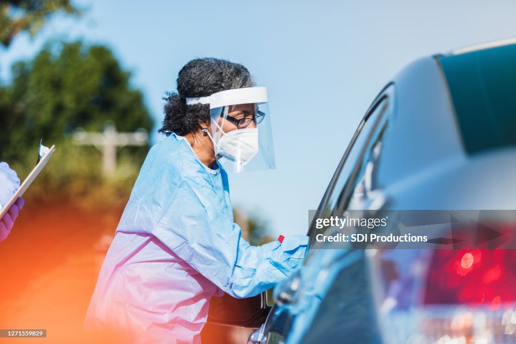 Une travailleuse de la santé administre COVID-19 au conducteur d’une voiture