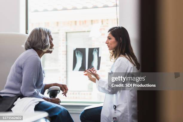 il medico premuroso discute la radiografia del piede del paziente - frattura foto e immagini stock