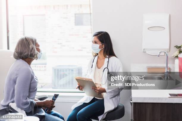 doctor discusses senior woman's health - female doctor with mask stock pictures, royalty-free photos & images