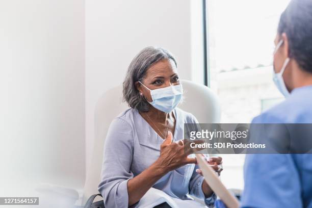 senior adult patient talks with doctor - covid-19 patient stock pictures, royalty-free photos & images