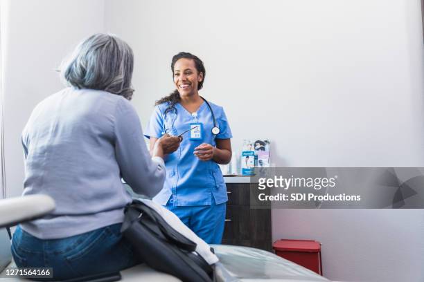 happy doctor talking with patient - blank pamphlet stock pictures, royalty-free photos & images