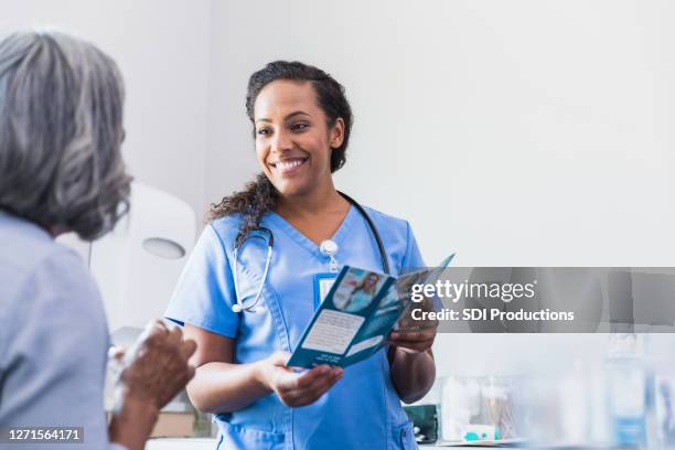 caring doctor discusses healthcare options with patient - blank pamphlet stock pictures, royalty-free photos & images