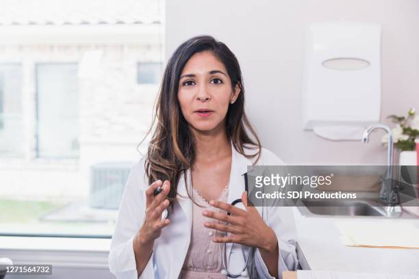 confident female doctor talks with patient durng virtual appointment - explaining stock pictures, royalty-free photos & images