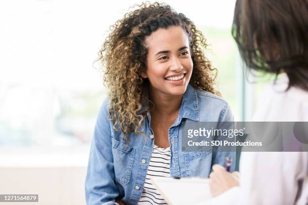 smiling female patient receives good news - young women stock pictures, royalty-free photos & images