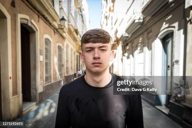 portrait of teenage boy standing in narrow street - serious teenager boy stock-fotos und bilder