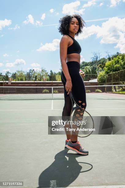 young woman standing on tennis court - running shoes sky stock-fotos und bilder