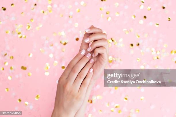 stylish female pink and white manicure. beautiful young woman's hands on pink pastel background with festive multicolored confetti. trendy geometric pattern. art manicure. - white rose flower spa photos et images de collection