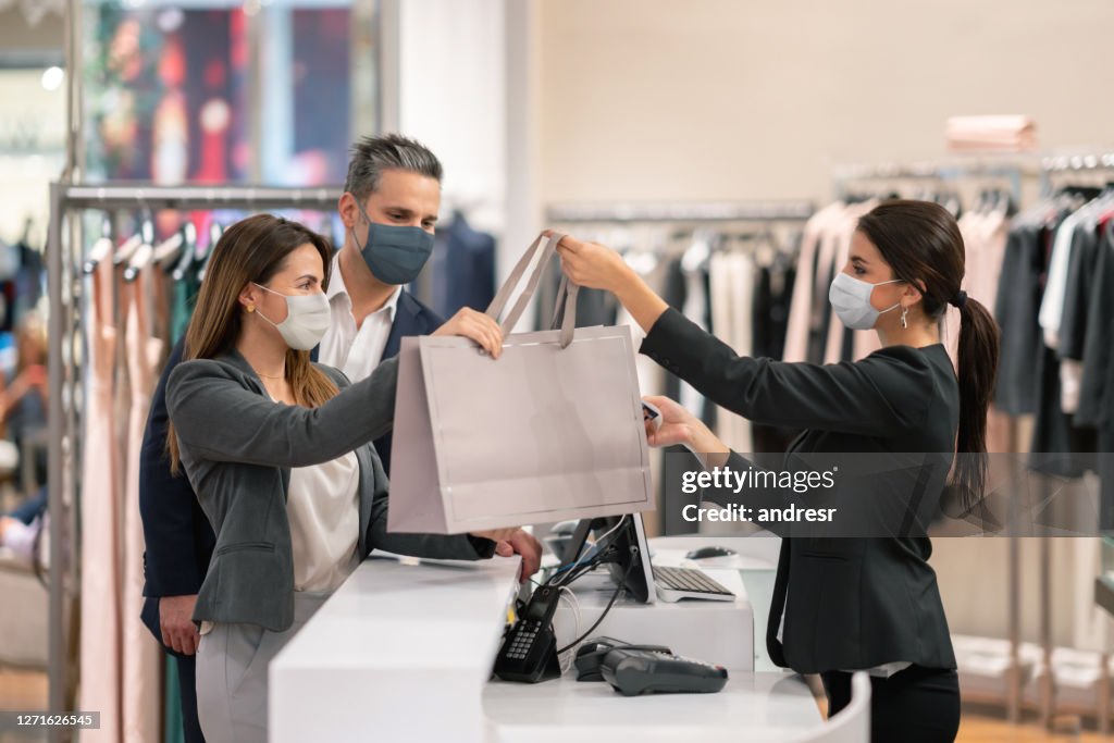 Paar einkaufen in einem Bekleidungsgeschäft und mit Gesichtsmasken während der Pandemie