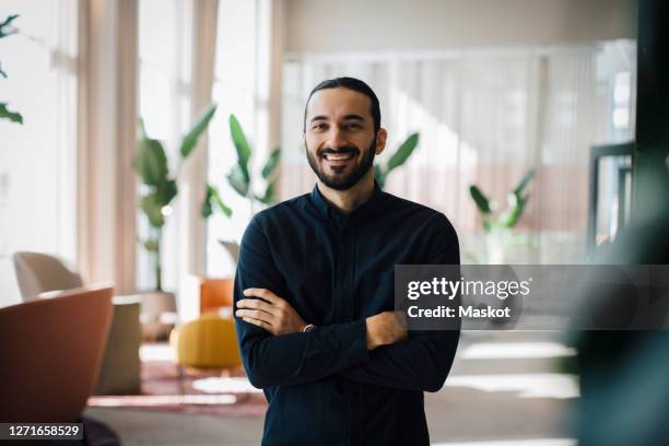 portrait of smiling businessman with arms crossed in office - etnias de oriente medio fotografías e imágenes de stock