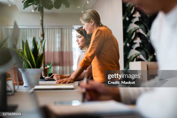 female business people working at table in office - collaborative working stockfoto's en -beelden