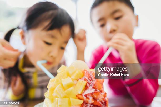 sibling eating shaved ice together - shaved ice stockfoto's en -beelden