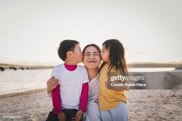 kids kissing mother  in the beach at dusk - asian mom kid kiss stock-fotos und bilder