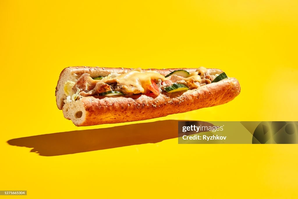 Fliegendes Hähnchen-Sandwich auf gelbem Hintergrund