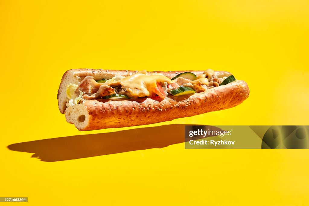 Flying chicken sandwich on yellow background
