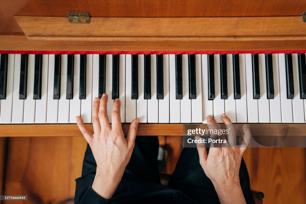 Woman practicing upright piano at home